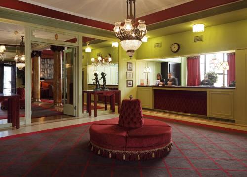 a lobby with a red chair and a bar at Grande Hotel do Porto in Porto