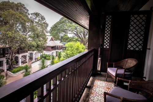 a patio area with chairs, tables, and a balcony at Na Nirand Romantic Boutique Resort in Chiang Mai