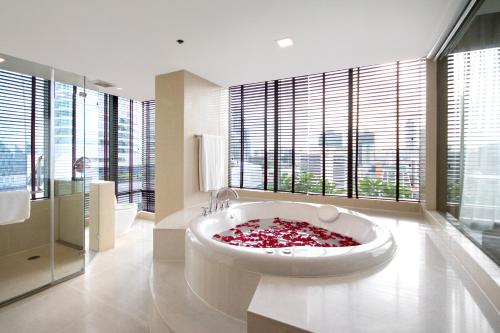 ein Badezimmer mit einer großen Badewanne und einem großen Fenster in der Unterkunft Sivatel Bangkok Hotel in Bangkok