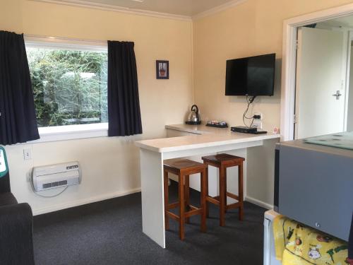 a room with a desk with a tv and a window at Alma Motel in Oamaru