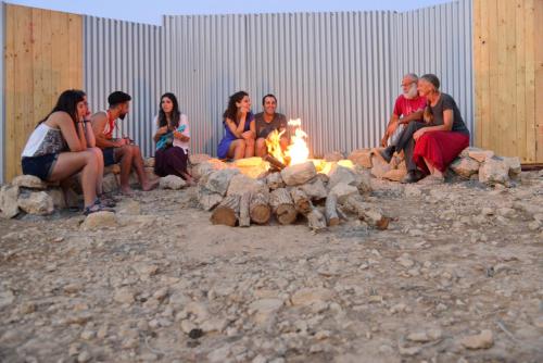 a group of people sitting around a fire at Tsavta in Mashabbe Sade