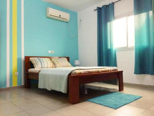 a bedroom with a bed with blue walls and a window at Princess Endale Residence in Douala