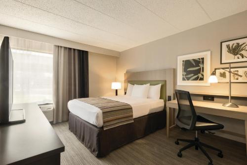 Cette chambre comprend un lit et un bureau. dans l'établissement Country Inn & Suites by Radisson, La Crosse, WI, à La Crosse