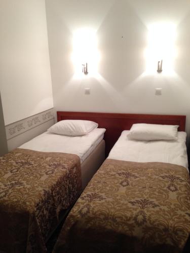 two beds in a hotel room with lights on the wall at Three Crowns Residents in Tallinn