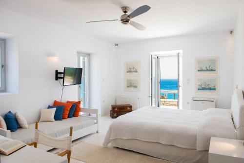 a white bedroom with a bed and a couch at Luxury Villa Seafront in Aliki