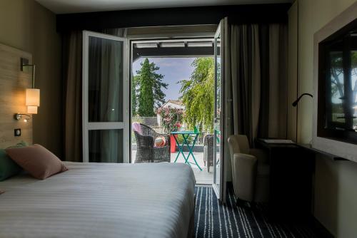 a hotel room with a bed and a door to a patio at Logis LE RABELAIS Hôtel- Restaurant - SPA in Fontenay-le-Comte