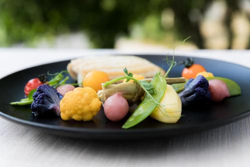 a plate of food with vegetables on a table at Logis LE RABELAIS Hôtel- Restaurant - SPA in Fontenay-le-Comte