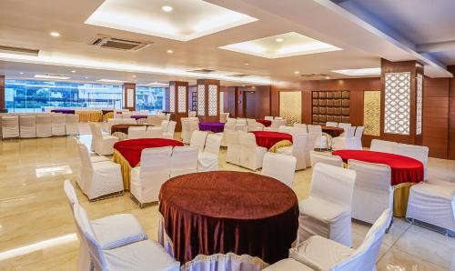 a banquet hall with white chairs and tables and red tables at Treebo Grand Legacy Elite With Roof Top Cafe in Dehradun