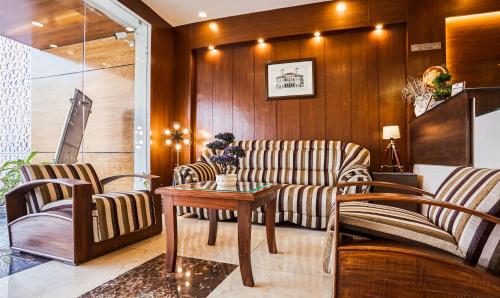 a living room with two couches and a table at Treebo Grand Legacy Elite With Roof Top Cafe in Dehradun