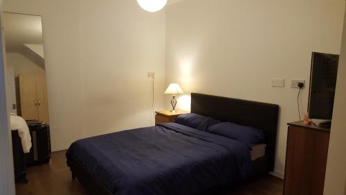 a bedroom with a blue bed and a television at The Heart Of Stratford..! in London