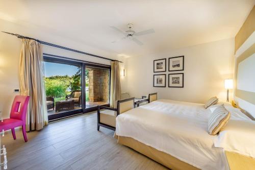 a bedroom with a bed and a large window at Hotel & SPA des Pecheurs in Bonifacio