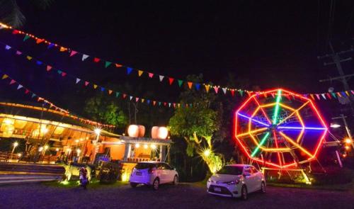 two cars parked next to a ferris wheel at night at The Mud - Eco Hotel in Ban Bang Po