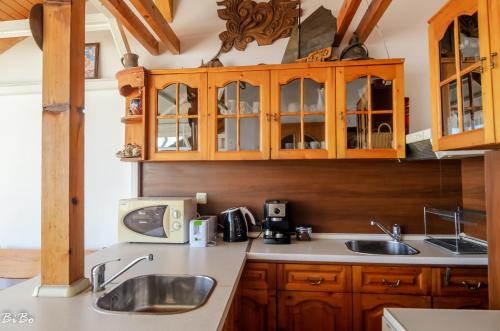 una cocina con armarios de madera y fregadero en Dom Mladenovi en Sozopol