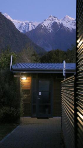 a building with snow capped mountains in the background at Sunset Motel in Fox Glacier