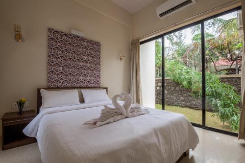 a bedroom with a white bed and a large window at StayVista's Greenwoods Villa 5 - City-Center Villa with Private Pool, Terrace, Lift & Music System in Lonavala