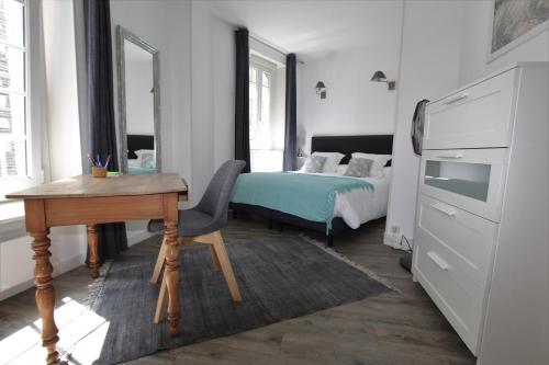 聖馬洛的住宿－L'Emeraude，一间卧室配有书桌、床和书桌、四柱床。