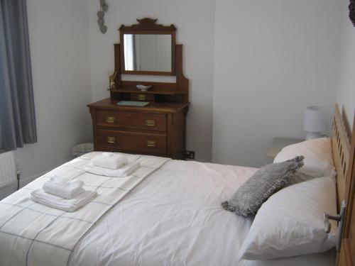 a bedroom with a bed with a dresser and a mirror at Drovers Cottage in Hayfield