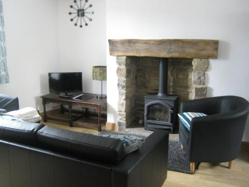 a living room with a couch and a fireplace at Drovers Cottage in Hayfield