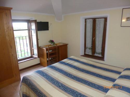 a bedroom with a bed and a dresser and two windows at Albergo La Foresteria in Bettolle