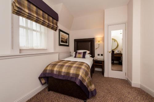 a bedroom with a bed and a window and a bathroom at Macdonald Inchyra Hotel & Spa in Falkirk