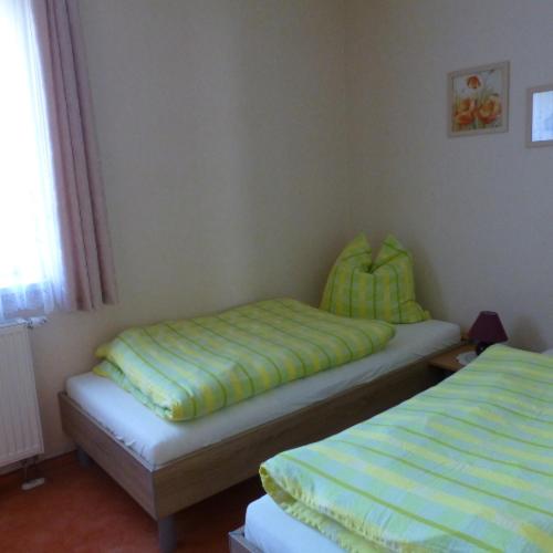 a bedroom with two beds with green sheets and a window at Ferienwohnung Junghans in Saalfeld