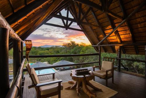 a room with chairs and a table on a deck at Vuyani Safari Lodge in Hoedspruit