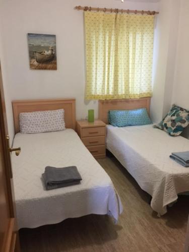 a bedroom with two beds and a window at Amarillo Apartment in Puerto de Mazarrón