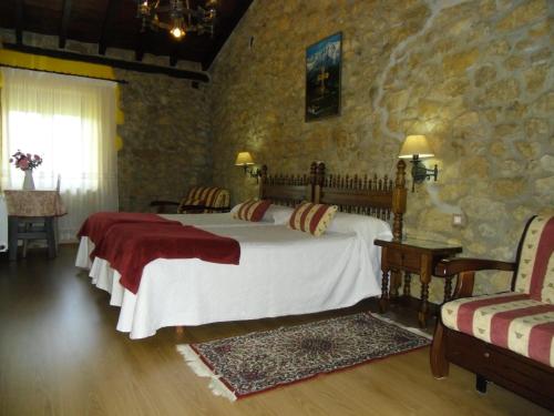 a bedroom with a bed and a stone wall at Posada Herrán in Santillana del Mar