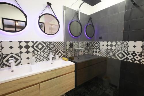 a bathroom with black and white tiles and a sink and mirrors at CasaCosy in Les Michels
