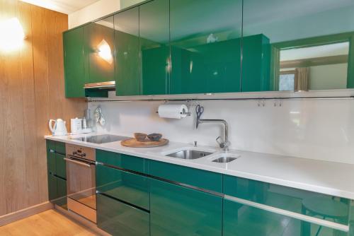 una cocina con armarios verdes y fregadero en Chesa Viroula - Zuoz en Zuoz