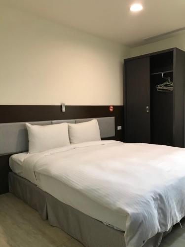 1 dormitorio con 1 cama grande con sábanas blancas en Big Bear Hotel, en Kaohsiung