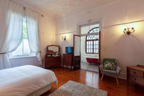 a bedroom with a bed and a mirror and a chair at Esperanza Guest House in Cape Town