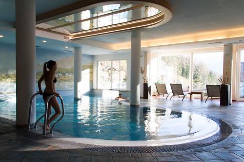 una mujer en bikini parada en una piscina en Berghotel Miramonti, en Tesero