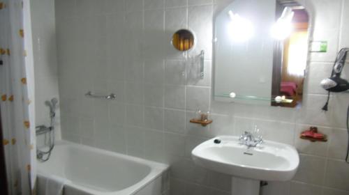 uma casa de banho branca com um lavatório e uma banheira em Posada Herrán em Santillana del Mar