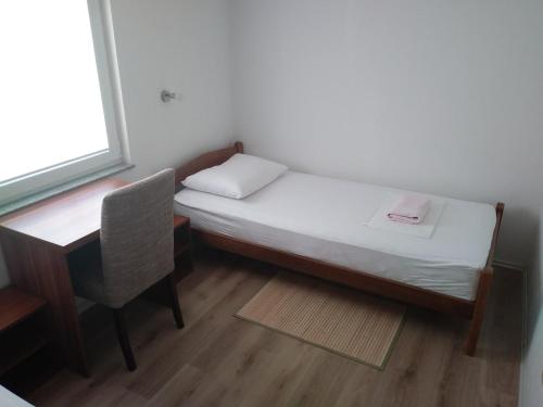 een klein bed en een bureau en een stoel in een kamer bij Guest House Andre in Međugorje