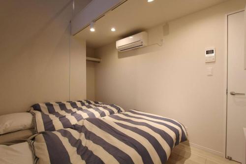 a bedroom with a bed with a striped blanket at Shibuya Anon #B102 in Tokyo