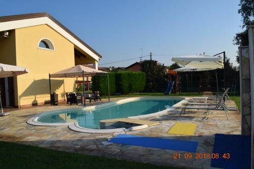 a swimming pool with chairs and umbrellas next to a house at Villa Posta Vecchia in Loreo