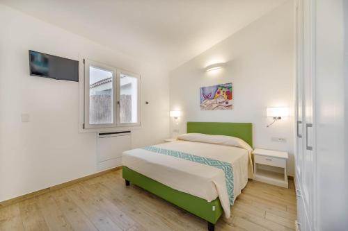 a white bedroom with a green bed and a window at Ville D'Ogliastra in Cardedu