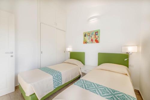 two beds in a room with white and green at Ville D'Ogliastra in Cardedu