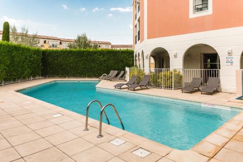 une piscine avec des chaises longues à côté d'un bâtiment dans l'établissement Garden & City Aix En Provence - Rousset, à Rousset
