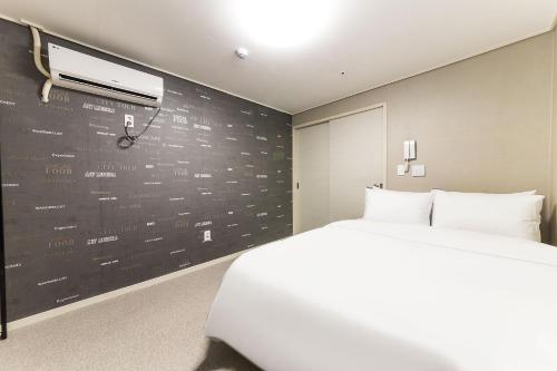 a bedroom with a white bed and a black wall at It's W in Suwon