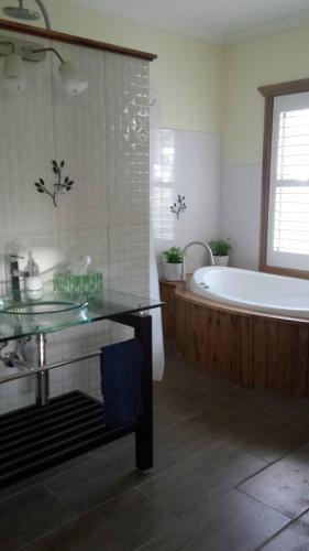 Stringybark Hills Retreat في Mylor: حمام مع حوض وطاوله زجاجيه