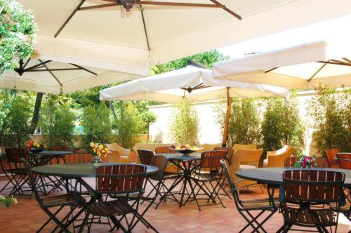 un patio al aire libre con mesas, sillas y sombrillas en Hotel Agathae, en Catania