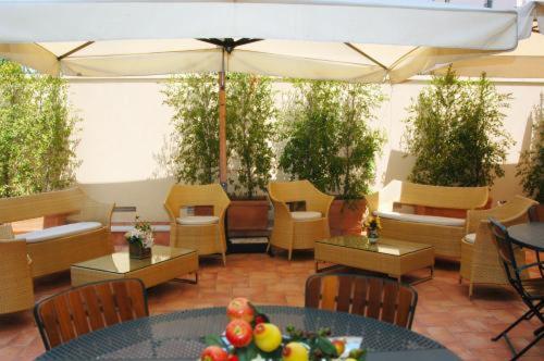 a patio with tables and chairs and an umbrella at Hotel Agathae in Catania