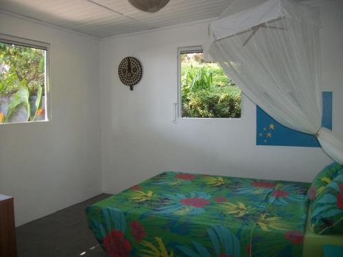 a bedroom with a bed and two windows at mango tree lodge in Bouillante