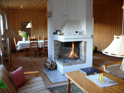 a living room with a fireplace and a table at Stora Björnstugan in Laisvall