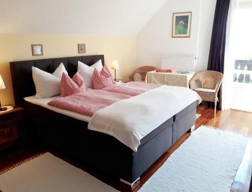 a bedroom with a large bed with red and white pillows at Bergbauernhof Stauder - Hirschbergalpakas in Lendorf
