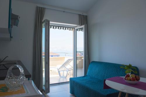 a living room with a blue couch and a balcony at Apartments and Rooms Lux in Senj