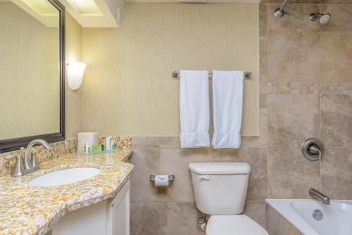 a bathroom with a toilet and a sink and a mirror at Isla Grand Beach Resort in South Padre Island