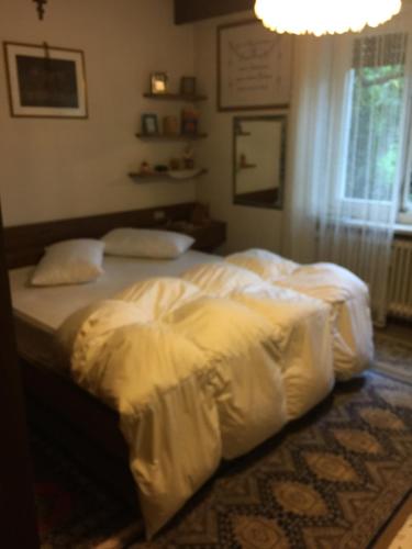 una camera con 2 letti, lenzuola bianche e un lampadario a braccio di Casa di vivian in montagna con giardino Alpe di siusi Fie allo sciliar Bolzano a Fié allo Sciliar